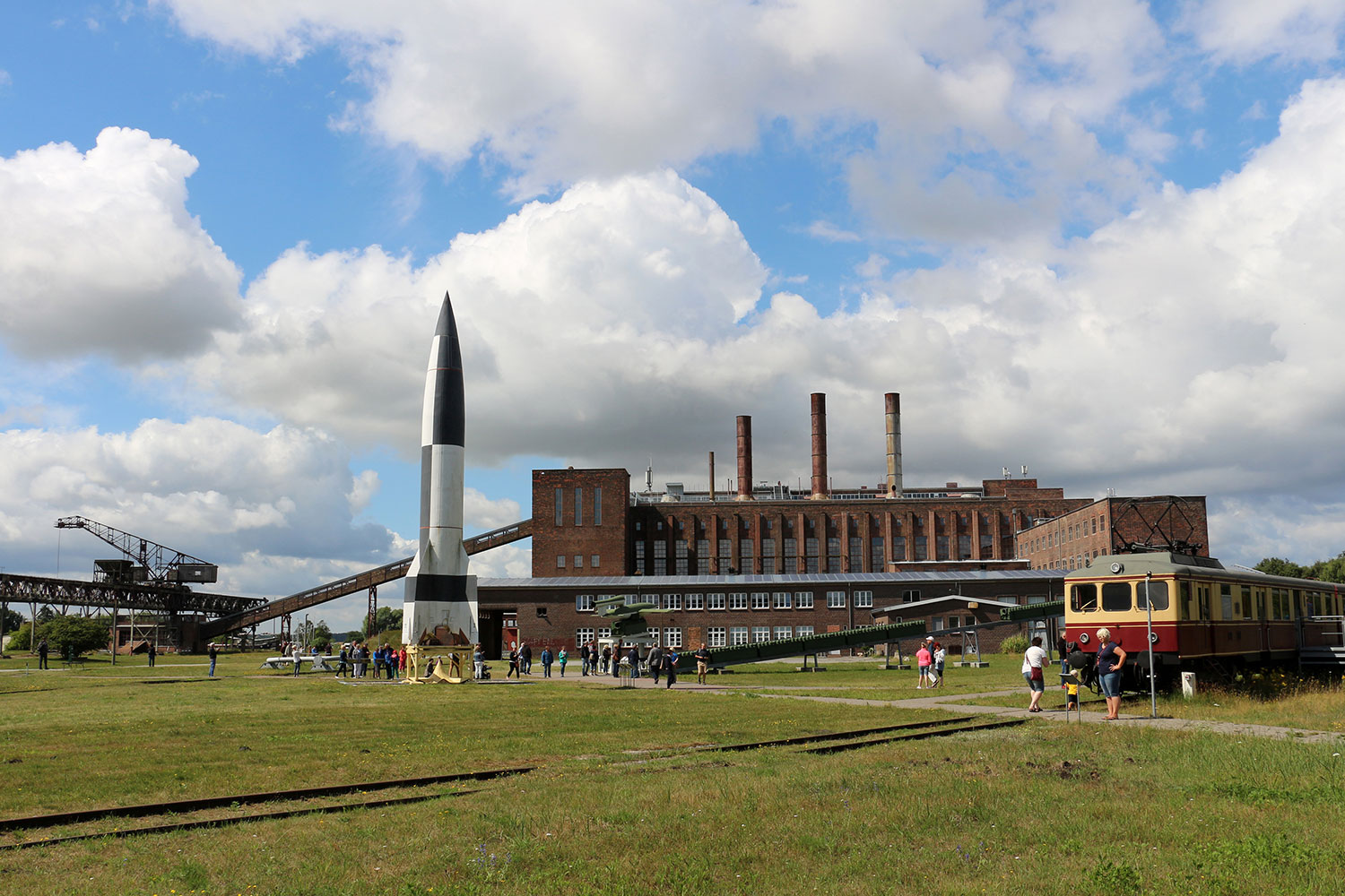 Foto des Außengeländes des Museums in Peenemünde. Eine Rakete und ein Eisenbahnwagon ist zu sehen.