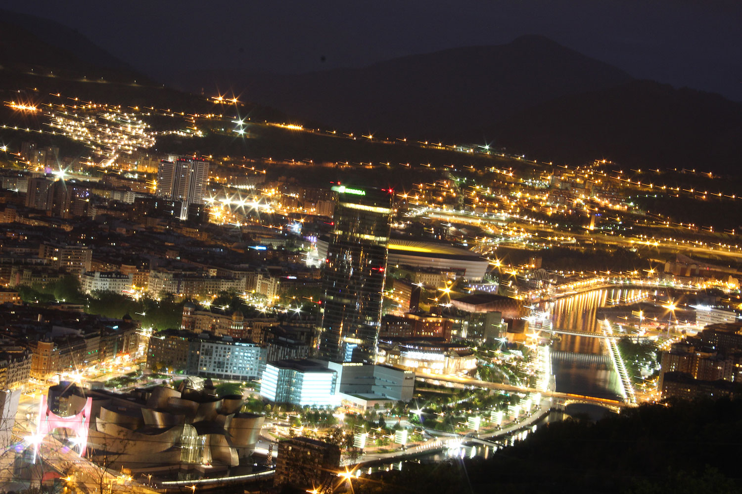 Nachtaufnahme mit Blick auf die erleuchtete Stadt Bilbao.