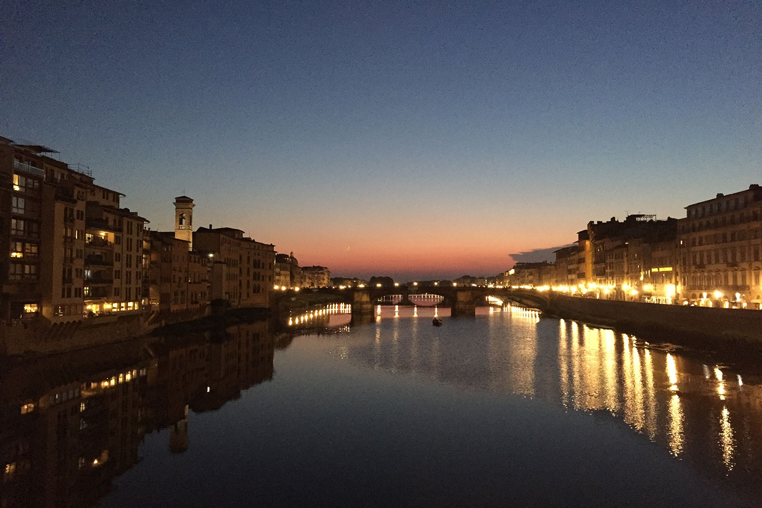 Zu sehen ist der Fluss Arno in der Dämmerung in der Stadt Florenz.