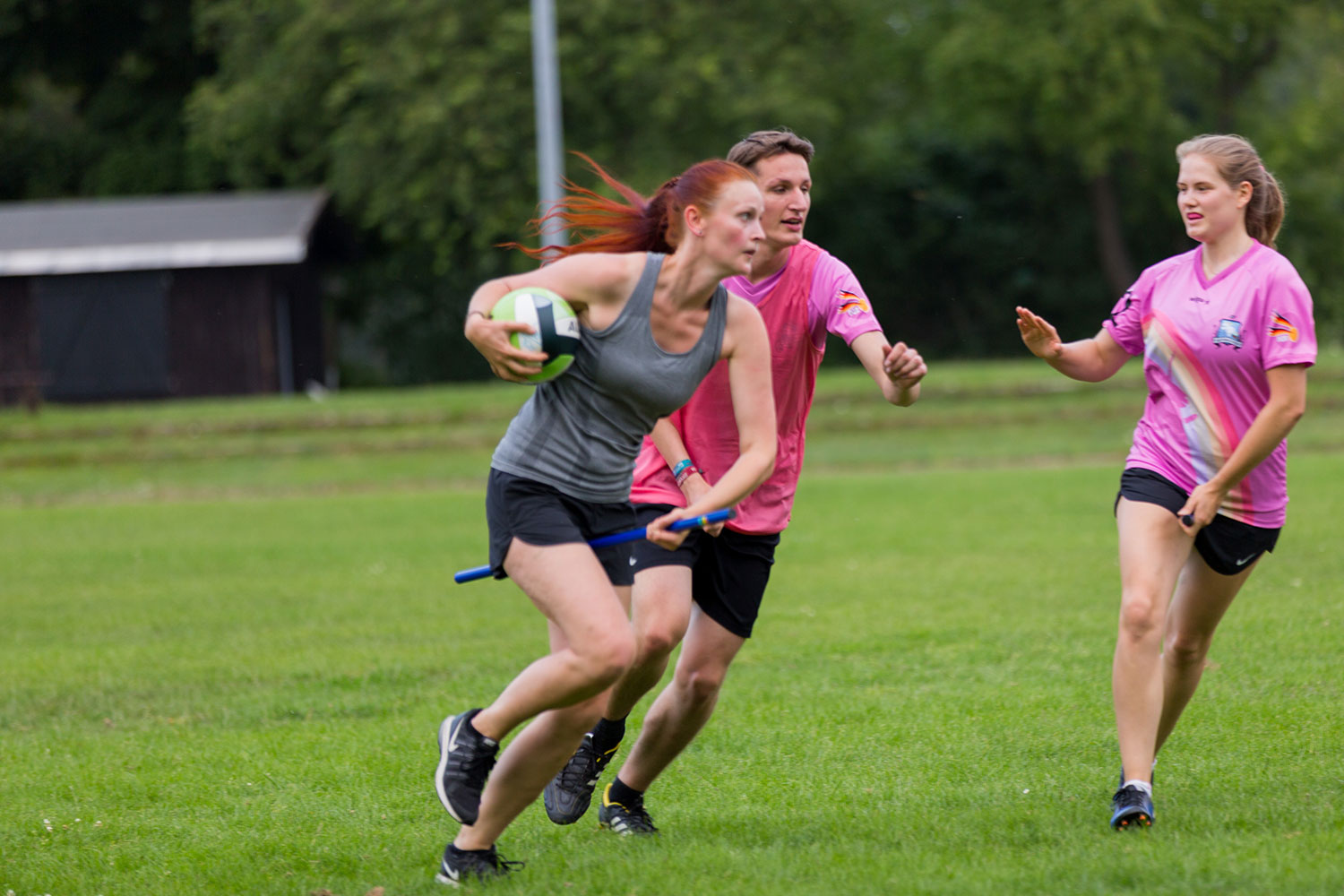 Eine Spielerin mit Besen und Ball ist in einer Angriffsposition im vollem Lauf zu sehen.