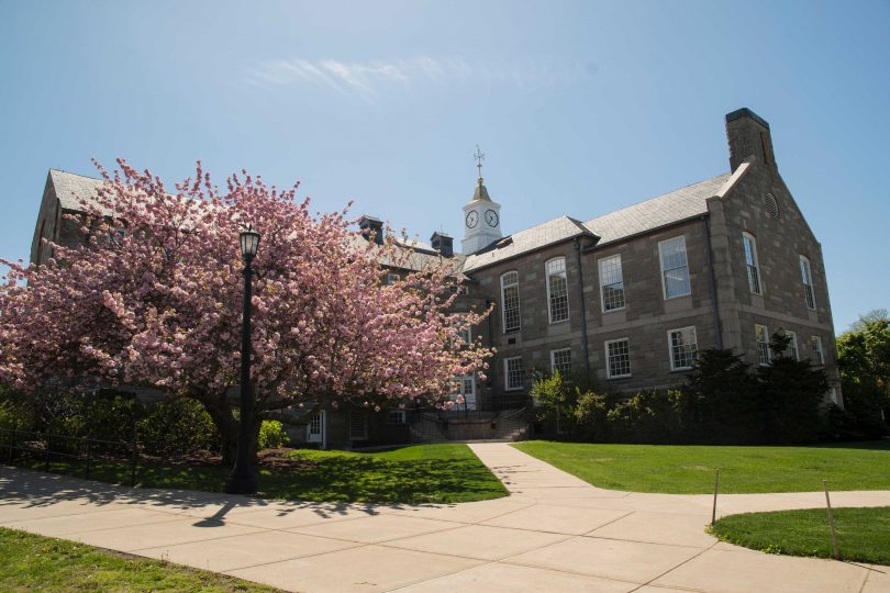 The picture shows a university building on the URI campus. In the foreground is a flowering cherry tree.