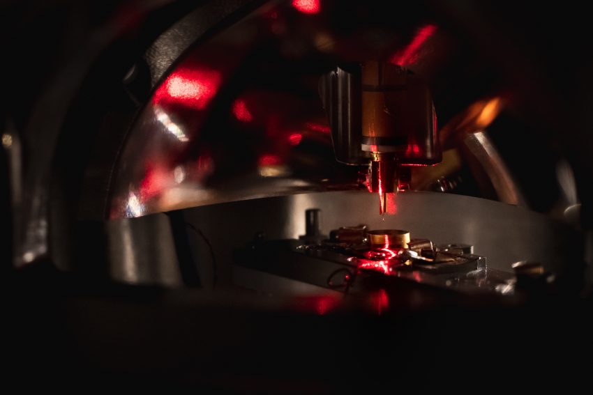 In the main chamber of the Photon-STM, the tip holder points from above to a pedestal made of stainless steel the size of a fingertip. The mirror of the microscope shimmeringly reflects the red illumination in the P-STM.