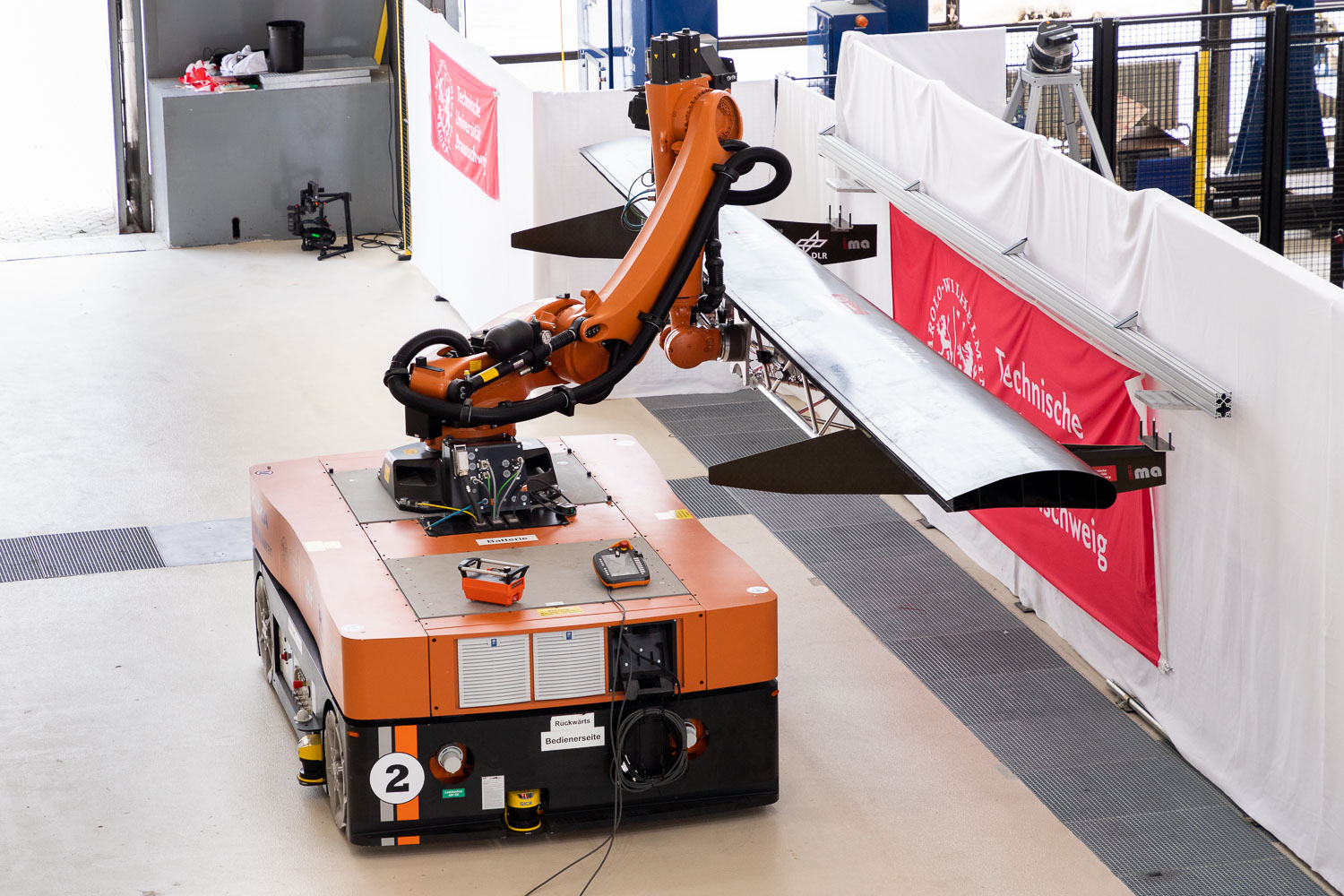 Der Roboterarm montiert das Klappenmodul am Flügel des Flugzeugs. Bildnachweis: Markus Hörster/TU Braunschweig