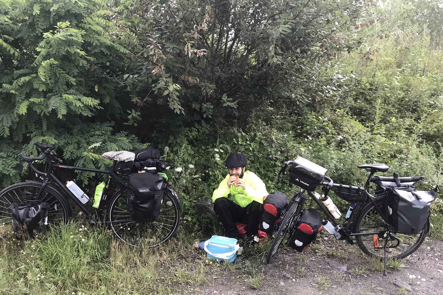 Moses Köhler sits next to his bicycle in rain gear.