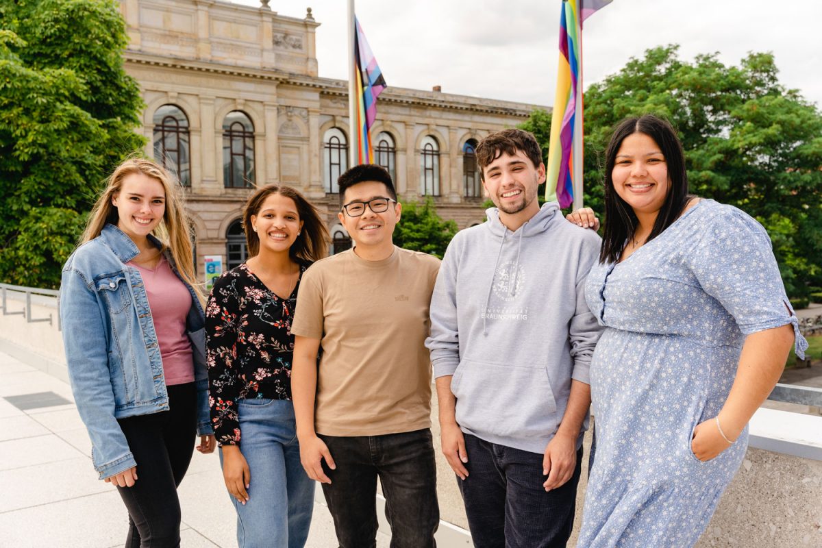 A group of students is standing in front of the old main building of TU Braunschweig for a photo.