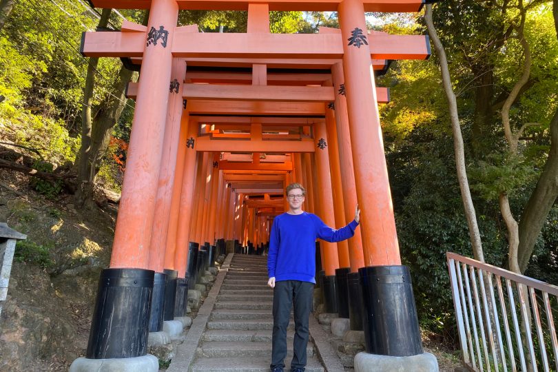 Der Student Dennis Kühn steht unter einem Torii-Tor in Kyoto.